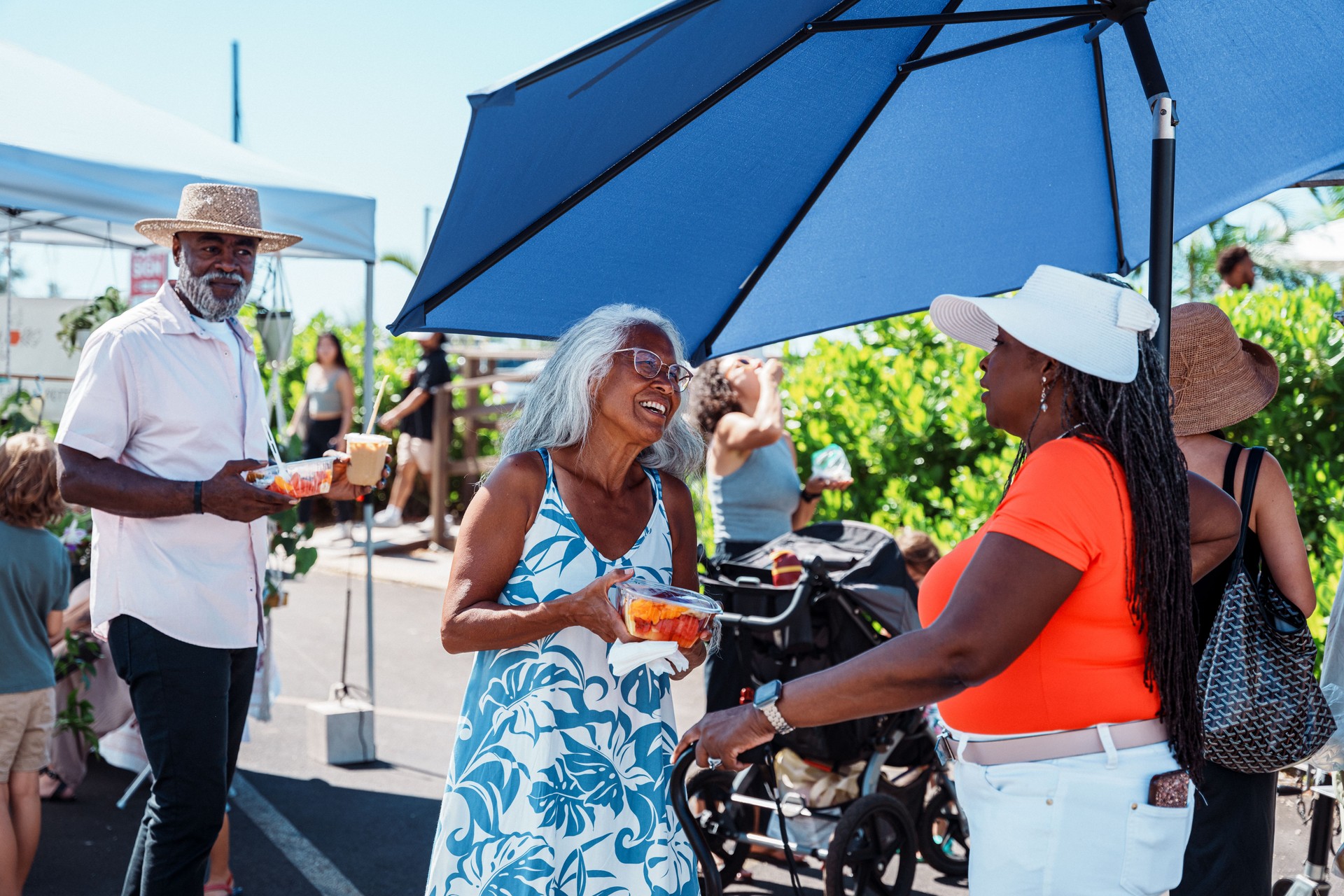 Hawaiian tour guide talking with African American tourists at street market